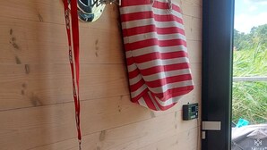 Un mur en bois avec un miroir, des clés et une serviette à rayures accrochée.