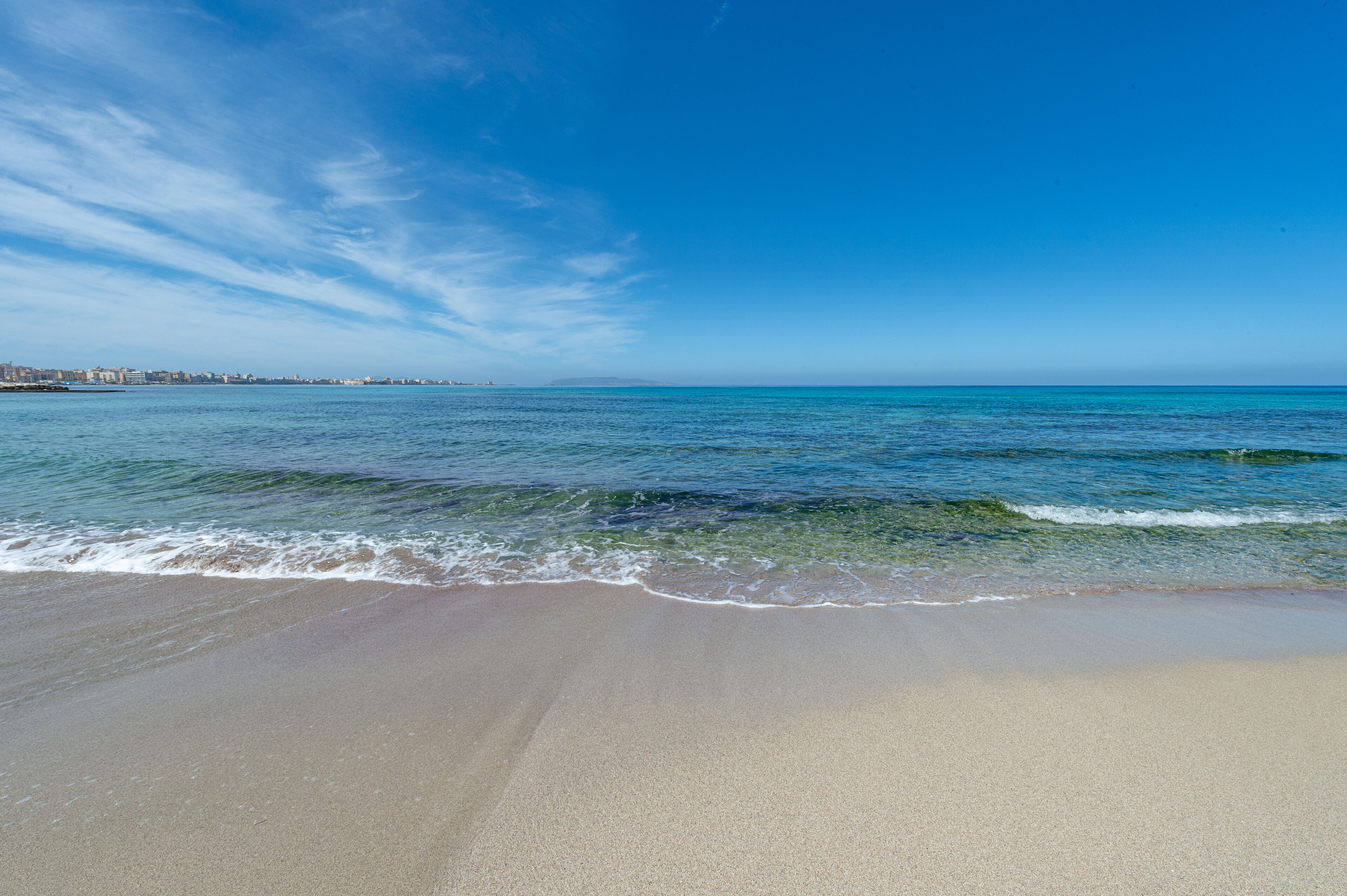 Una playa con agua azul cristalina y una orilla arenosa.