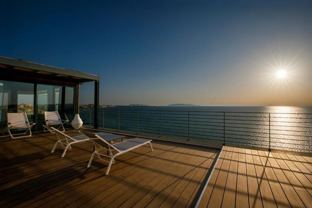 Una terrazza con poltrone relax e vista sul mare al tramonto.