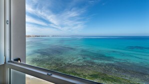 Blick von einem Balkon auf ein türkisblaues Meer unter blauem Himmel.