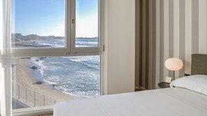 Ein Schlafzimmer mit großem Fenster mit Blick auf Strand und Meer.