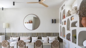 Un comedor moderno con un espejo redondo, un ventilador de techo y una pared con estantes que exhiben objetos decorativos.