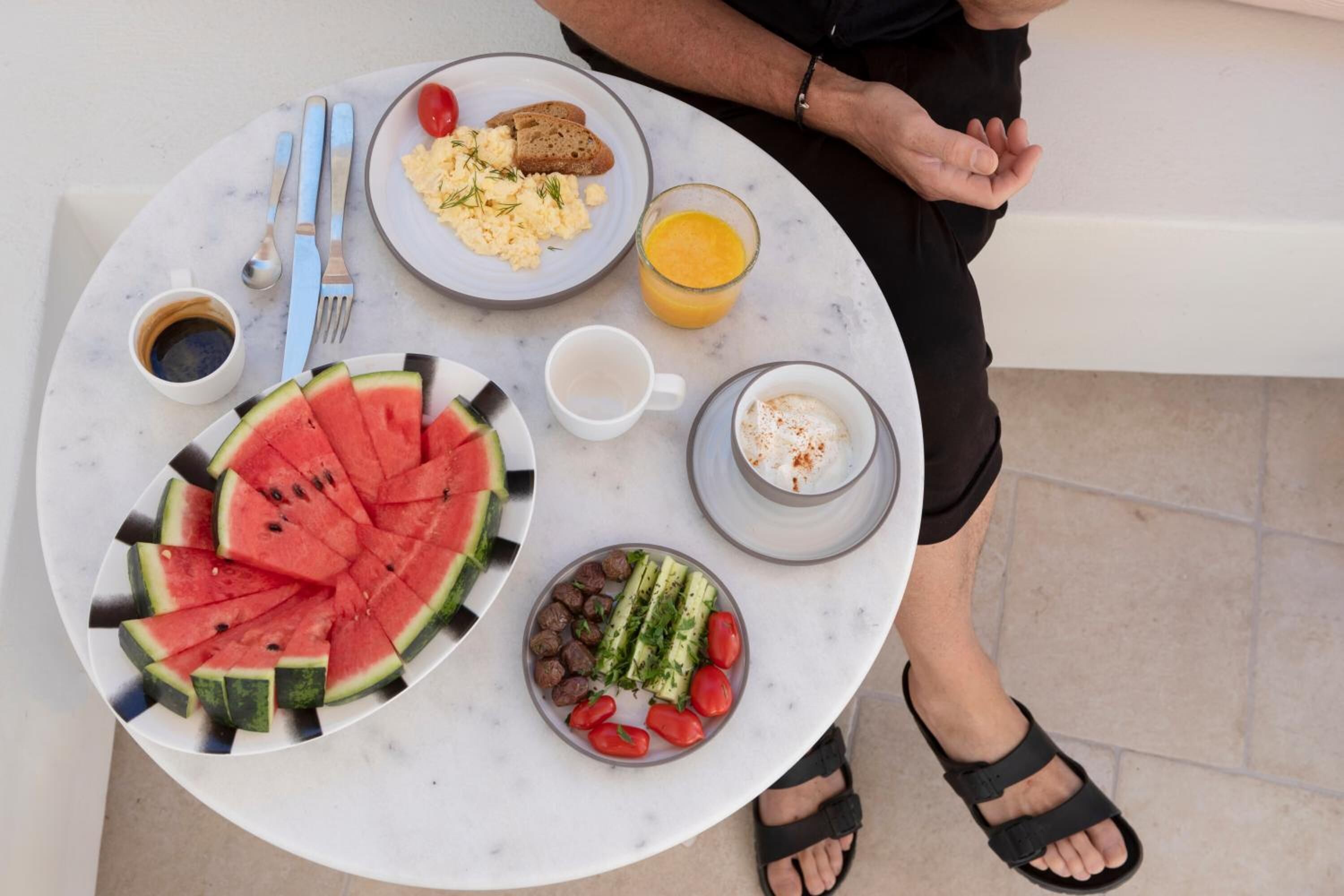 A breakfast table with plates of food, a glass of orange juice, and a cup of coffee.