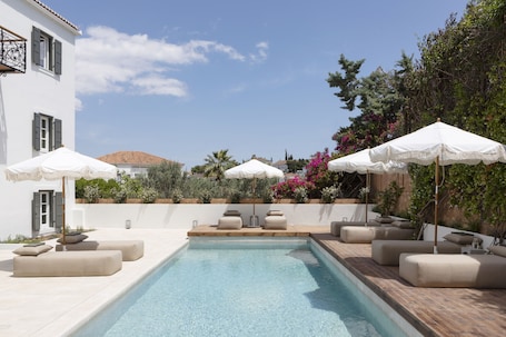 Una piscina al aire libre, sillones reclinables de piscina