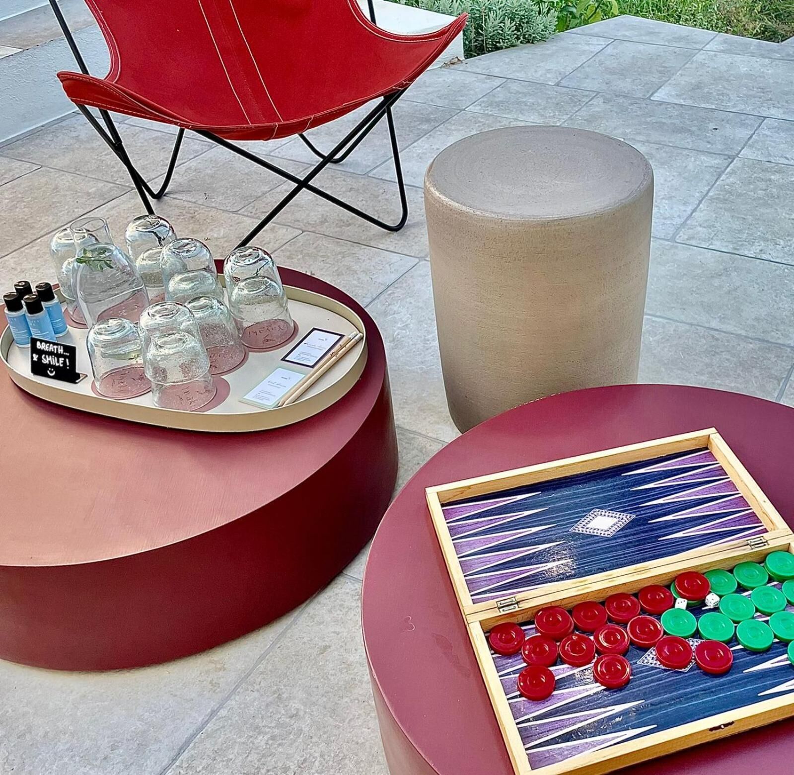 A red chair, a round table with a tray of glasses and bottles, and a game table with poker chips and playing cards.