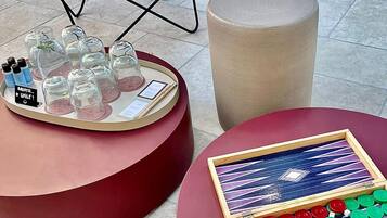 A red chair, a round table with a tray of glasses and bottles, and a game table with poker chips and playing cards.