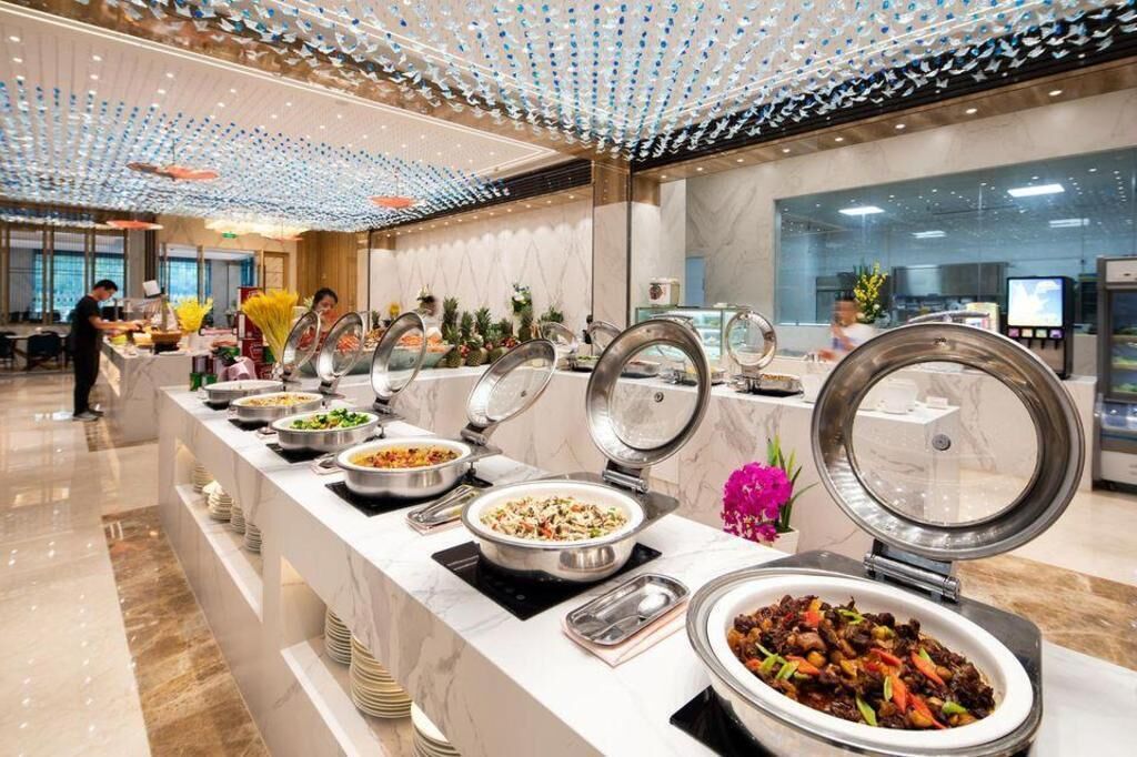 A buffet setup with multiple food stations, a marble counter, and a modern ceiling design.