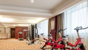 Une chambre d’hôtel équipée d’un vélo d’exercice rouge, d’un vélo stationnaire et d’un appareil de musculation.