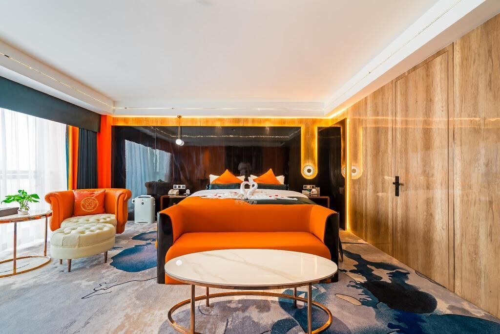 Habitación de hotel moderna con una cama grande, una mesa redonda, un sofá y vistas a la ciudad.