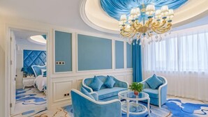 Une pièce aux couleurs bleu et blanc, agrémentée d’un lustre, de deux canapés, d’une table basse et d’un tapis à motifs.