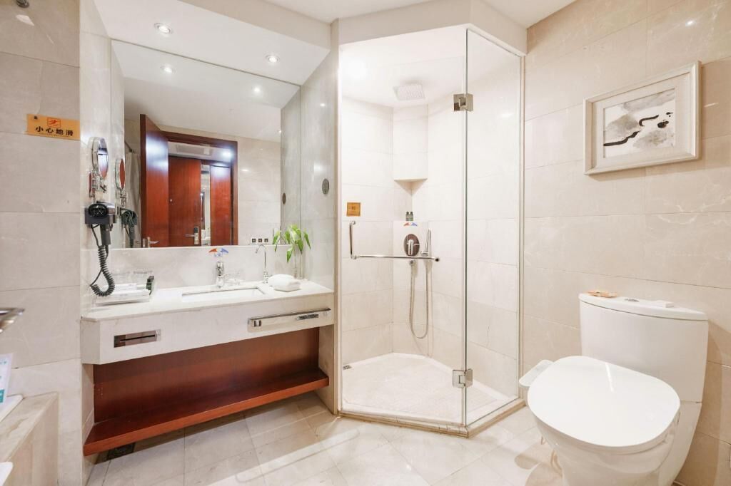 A modern bathroom with a glass-enclosed shower, a sink with a mirror, and a toilet.