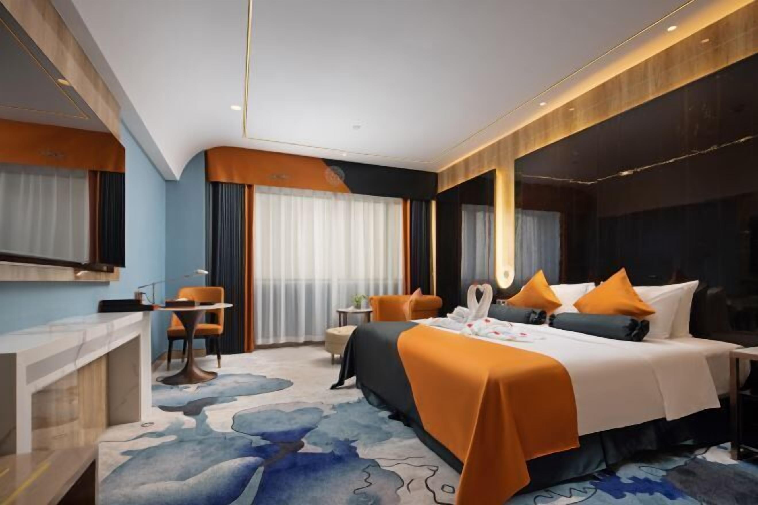 Ein modernes Hotelzimmer mit einem großen Bett, einem Schreibtisch und einer Sitzecke.
