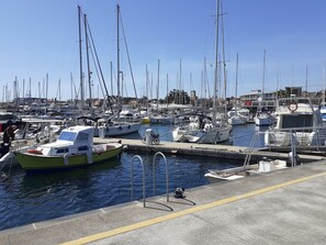 Un port de plaisance où sont amarrés plusieurs bateaux, un cycliste et une personne qui travaille sur un bateau.