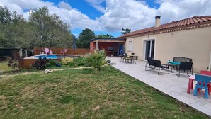 Un patio trasero con piscina, mobiliario de jardín y una pequeña construcción con techo de tejas.