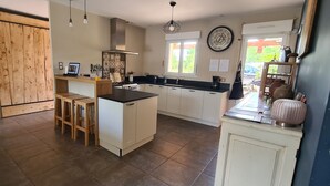 Una cocina con una isla central, taburetes de madera, una estufa y un ventanal.