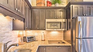 Una cocina con armarios oscuros, electrodomésticos de acero inoxidable, encimeras de granito y un reverso de ladrillo.