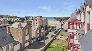 Ett bostadsområde vid kusten med byggnader av sten, en strand och en klar himmel.
