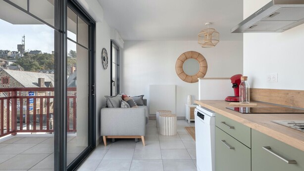Un apartamento moderno con balcón, una cocina con encimera de madera y una zona de comedor con mesa y sillas redondas.