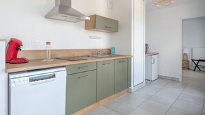Una cocina moderna con lavavajillas, una cafetera roja, un tarro de vidrio y una encimera de madera.