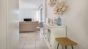 A modern living room with a beige sofa, a white cabinet, and a wicker chair. - Nice flat for 6, sea view, 50m from the beach (Pléneuf-Val-André)