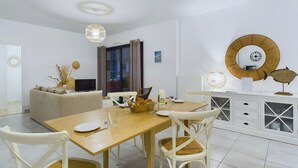 Een moderne eetruimte met een houten tafel, witte stoelen en een witte kast met glazen deuren.