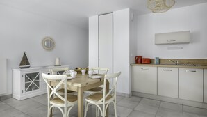 Una cocina moderna con armarios blancos, una mesa de comedor de madera y sillas blancas.