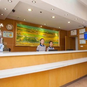 A reception desk with a large landscape painting above it, a clock, and various certificates on the wall. - 7 Days Inn (Shanghai)