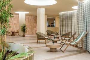 Un área de estar moderna con mobiliario de mimbre, una piscina y vistas al interior.