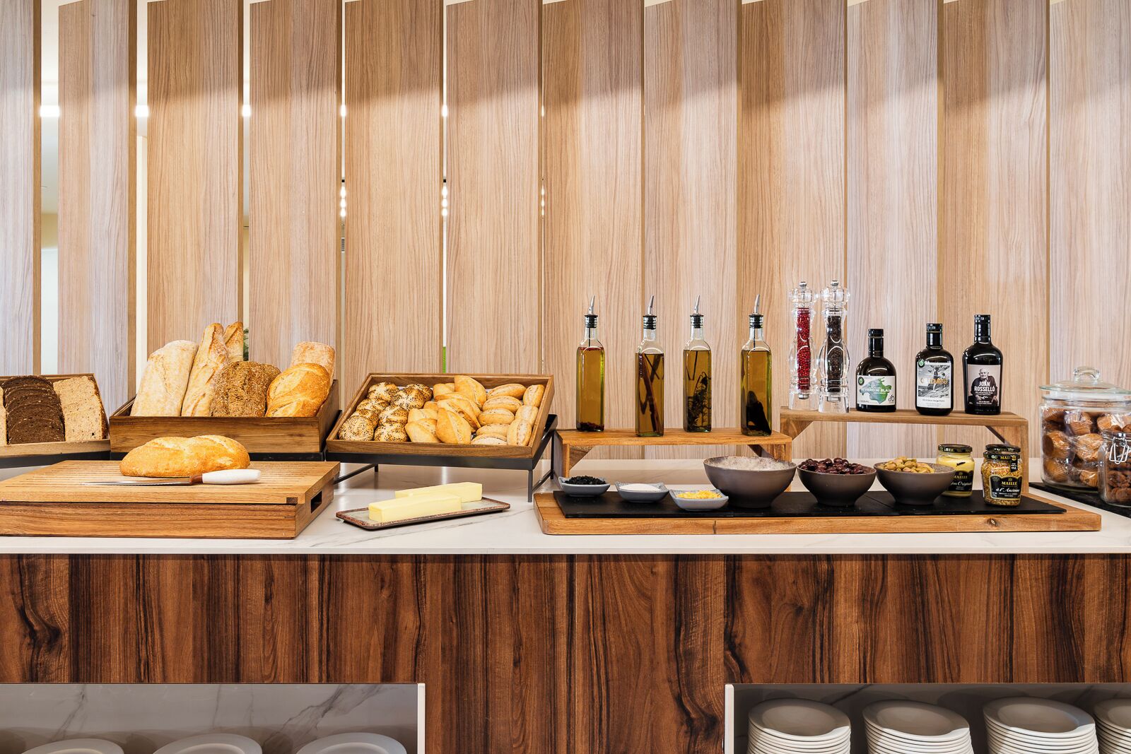 A breakfast buffet with various breads, pastries, and condiments.