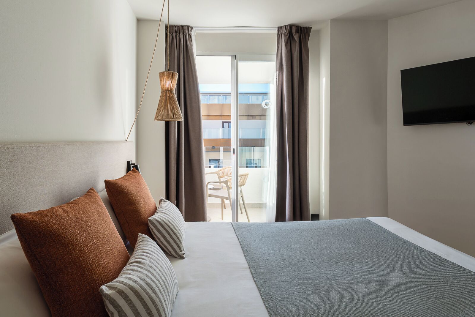 Une chambre d’hôtel dotée d’un grand lit, d’une télévision à écran plat et d’un balcon offrant une vue sur la ville.