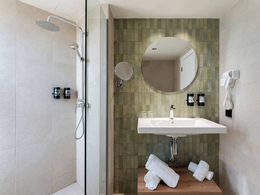 Un baño moderno con ducha, lavamanos y espejo.