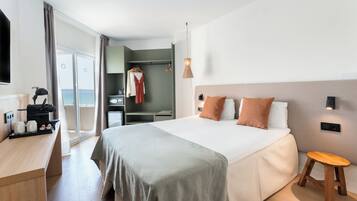 A modern hotel room with a bed, bedside table, and a view of the sea through the window.
