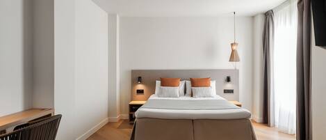 A modern hotel room with a large bed, bedside tables, a desk, and a chair.