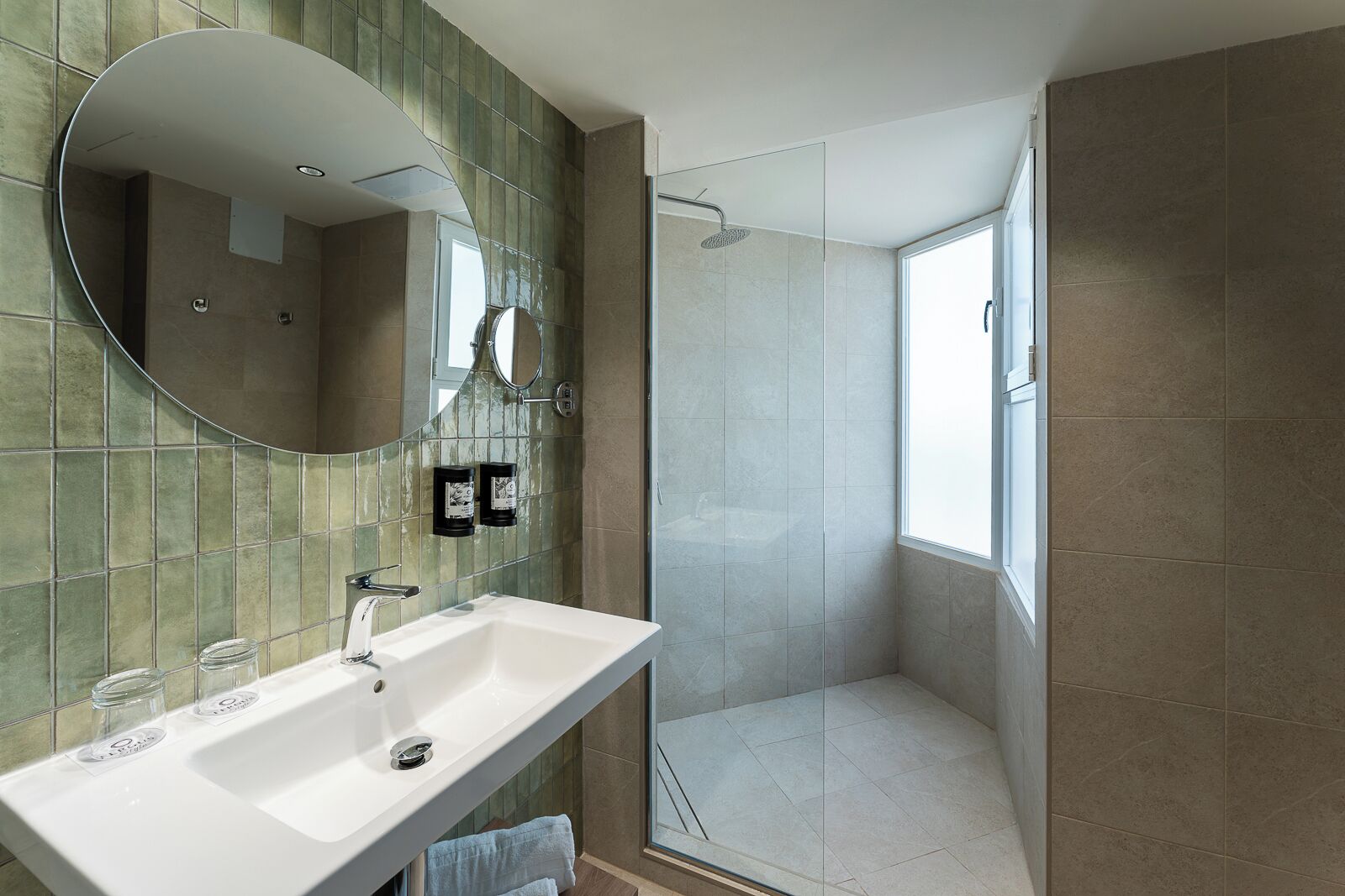 Une salle de bain moderne avec un grand miroir, un lavabo blanc et une douche à parois de verre.