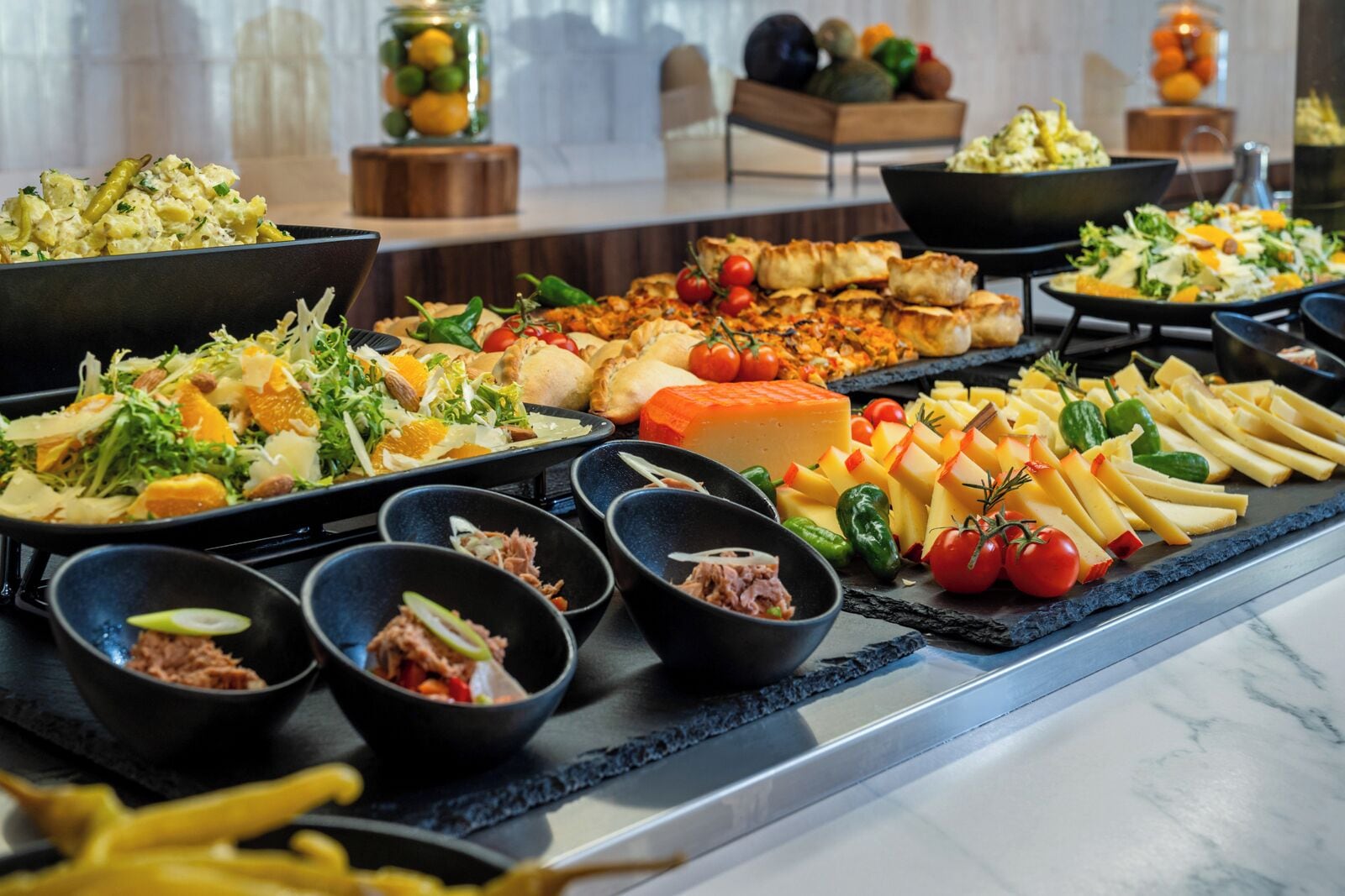 Ein reichhaltiges Buffet mit verschiedenen Speisen, darunter Salate, Käse und Fleisch.