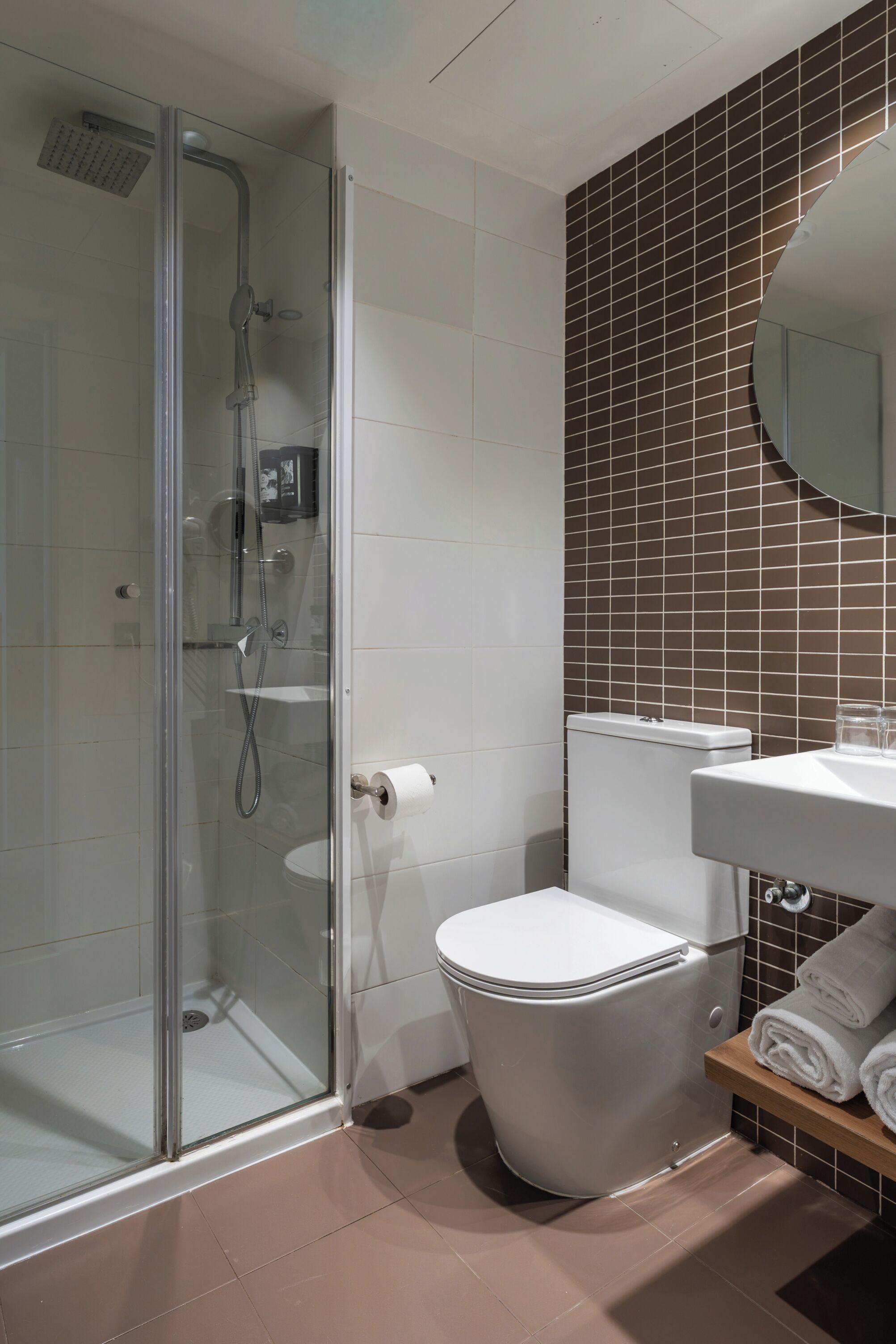 A modern bathroom with a glass shower enclosure, a toilet, and a sink with a mirror.
