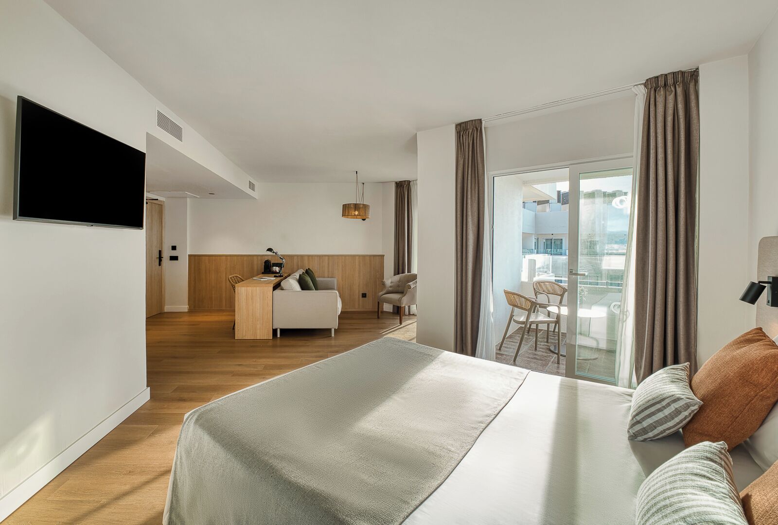 Een moderne hotelkamer met een bed, een bureau en een balkon.