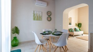 A dining area with a round table, white chairs, and a green plant. - Villa Vanessa - Noto (Noto)