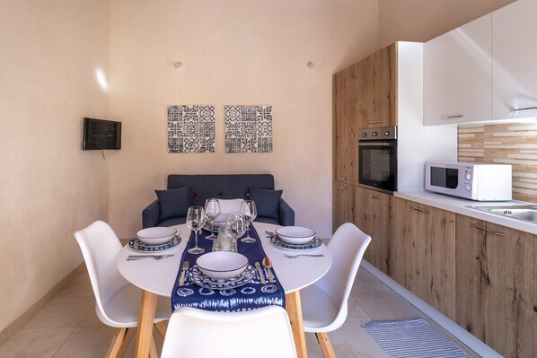 A modern kitchen with white cabinets, a microwave, and a dining area with a table set for four.