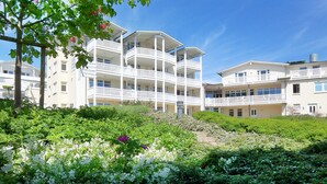 Ein mehrstöckiges Hotel mit Balkonen, umgeben von üppiger Vegetation und blühenden Pflanzen.