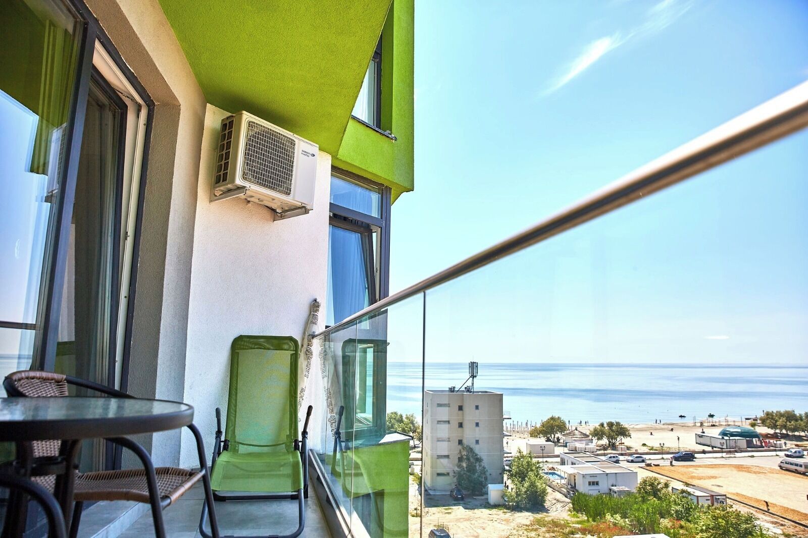 Varanda com vista para o mar, uma cadeira, uma mesa e um aparelho de ar condicionado.