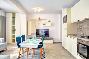 A modern kitchen with white cabinets, a built-in oven, and a TV on a stand. - Aparthotel Ella Alezzi (Navodari)