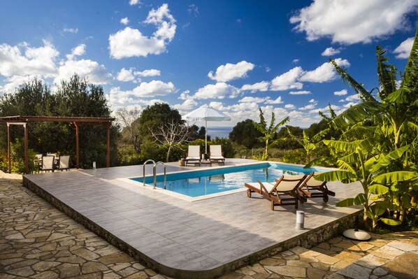 A rectangular swimming pool with two lounge chairs and a pergola.