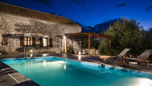 A stone building with a swimming pool, outdoor seating, and a pergola. - 1841 Petrino (Kefalonia)