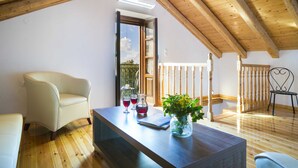 A cozy room with a wooden ceiling, a sofa, a table with drinks and a vase, and a view through a door. - 1841 Petrino (Kefalonia)