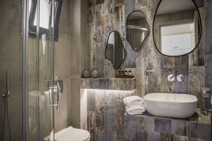 Un baño moderno con cabina de ducha de vidrio, bañera independiente y tocador con espejo.