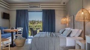 A bedroom with a bed, a sofa, a table, and a TV. - Avithos Resort (Kefalonia)