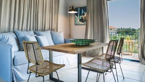 A modern living room with a sofa, chairs, a table, and a view of a balcony. - Avithos Resort (Kefalonia)