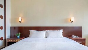 A hotel room with a large bed, two bedside tables, a wooden headboard, and two wall-mounted light fixtures. - Guang Xin Hotel (Shenzhen)