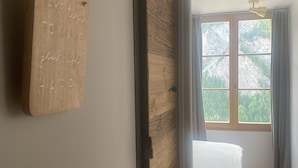 Ein Zimmer mit einem Bett, einer Holzwand und einem Fenster mit Blick auf Bäume.